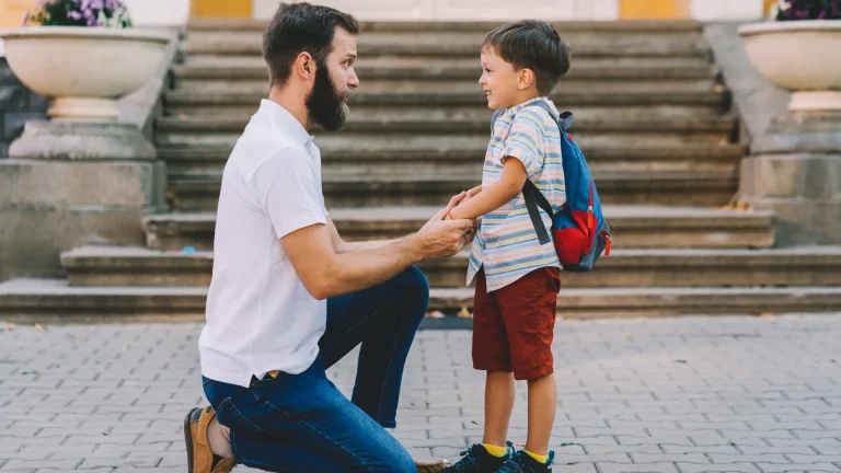 Father kneeling and holding hands with his young child